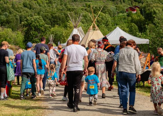 Bilder viser voksne og barn som går på en grusvei med lavoer i bakgrunnen.